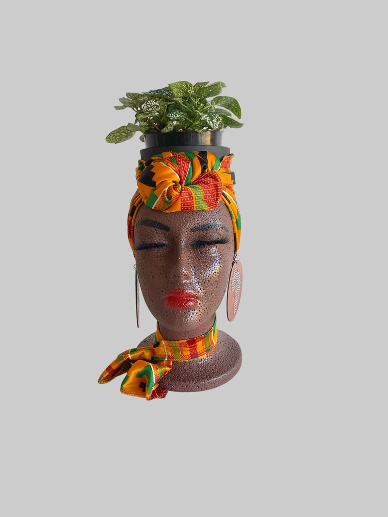 Head planter with colorful scarf and plant on a white background