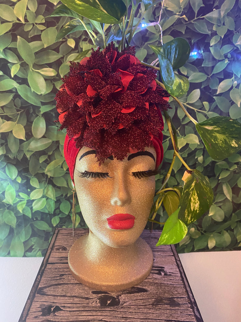 Decorative head with red floral arrangement against a green leafy background